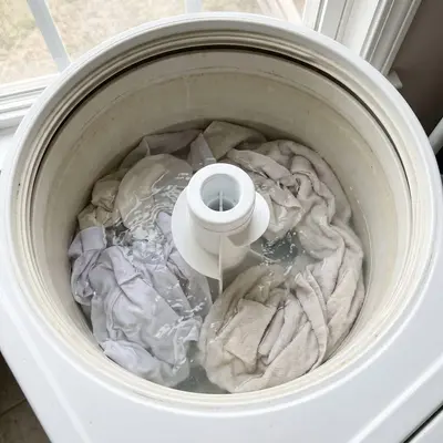 Tanquinho visto de cima com roupas e água no cesto